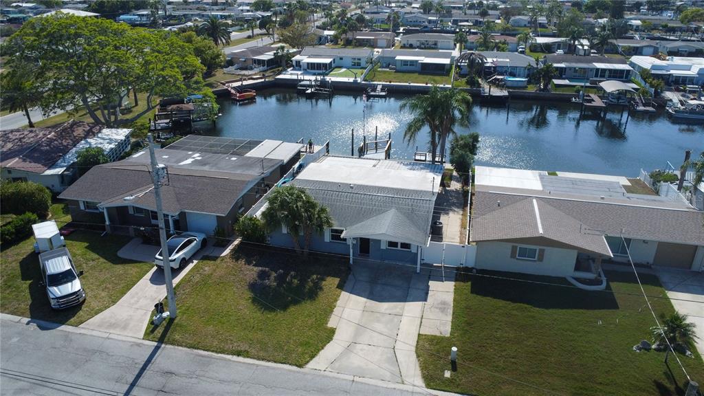 An aerial view shows three suburban houses situated along a canal with private boat docks — 12739 1ST ISLE, HUDSON, FL