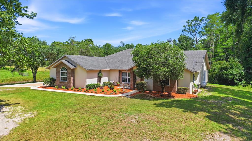 A single-story house with a beige exterior, brick accents, and a large front yard — 19113 QUINLAN ST, ORLANDO, FL