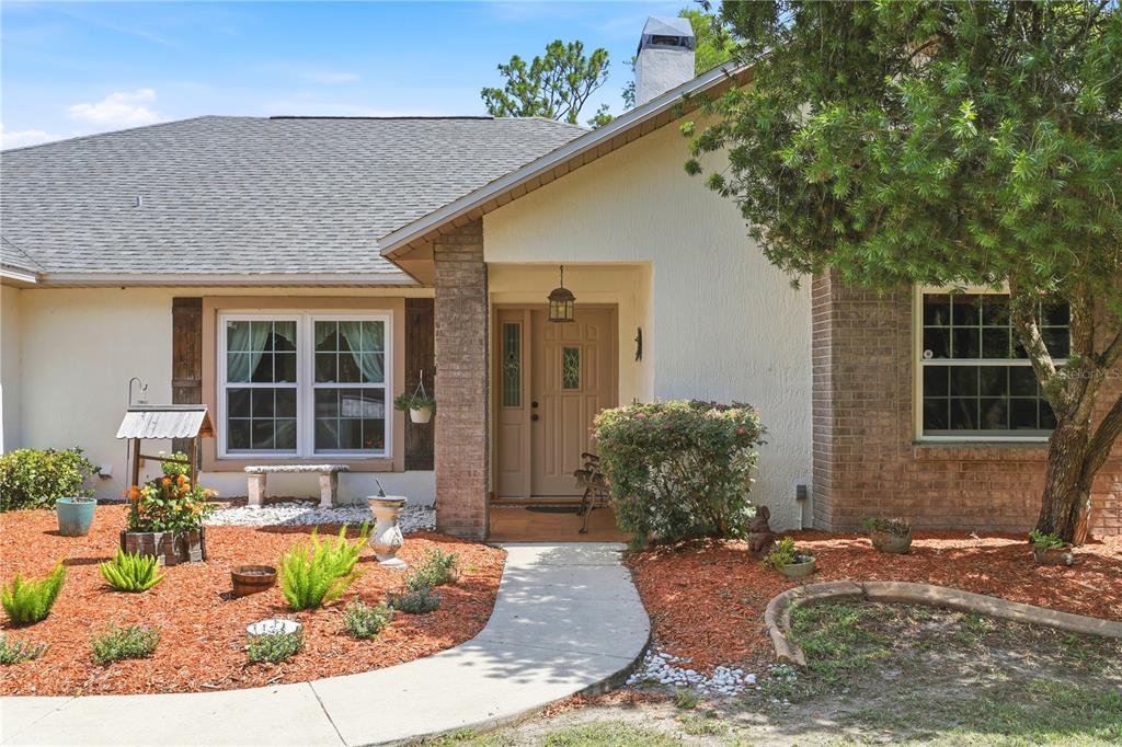 A single-story house with a tan stucco exterior, brick accents, and a front walkway — 19113 QUINLAN ST, ORLANDO, FL