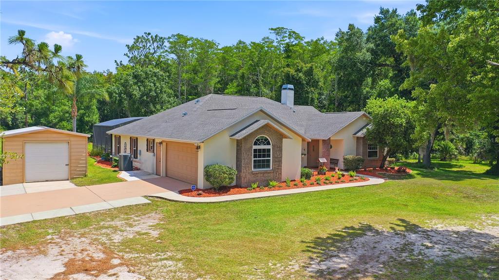 A single-story house with a tan exterior, brick accents, a two-car garage, and a shed — 19113 QUINLAN ST, ORLANDO, FL