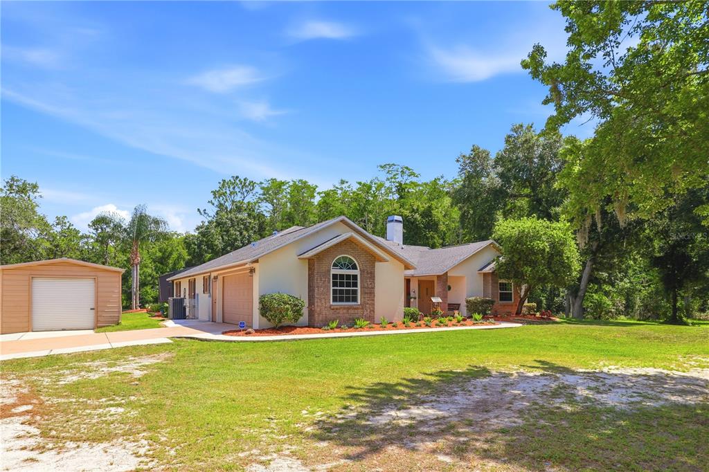 A single-story house with a brick facade, attached garage, and a separate metal storage shed — 19113 QUINLAN ST, ORLANDO, FL