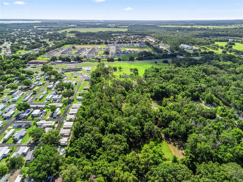 An aerial view shows a wooded lot adjacent to a residential neighborhood and mobile home park — 26043 US HIGHWAY 27, LEESBURG, FL