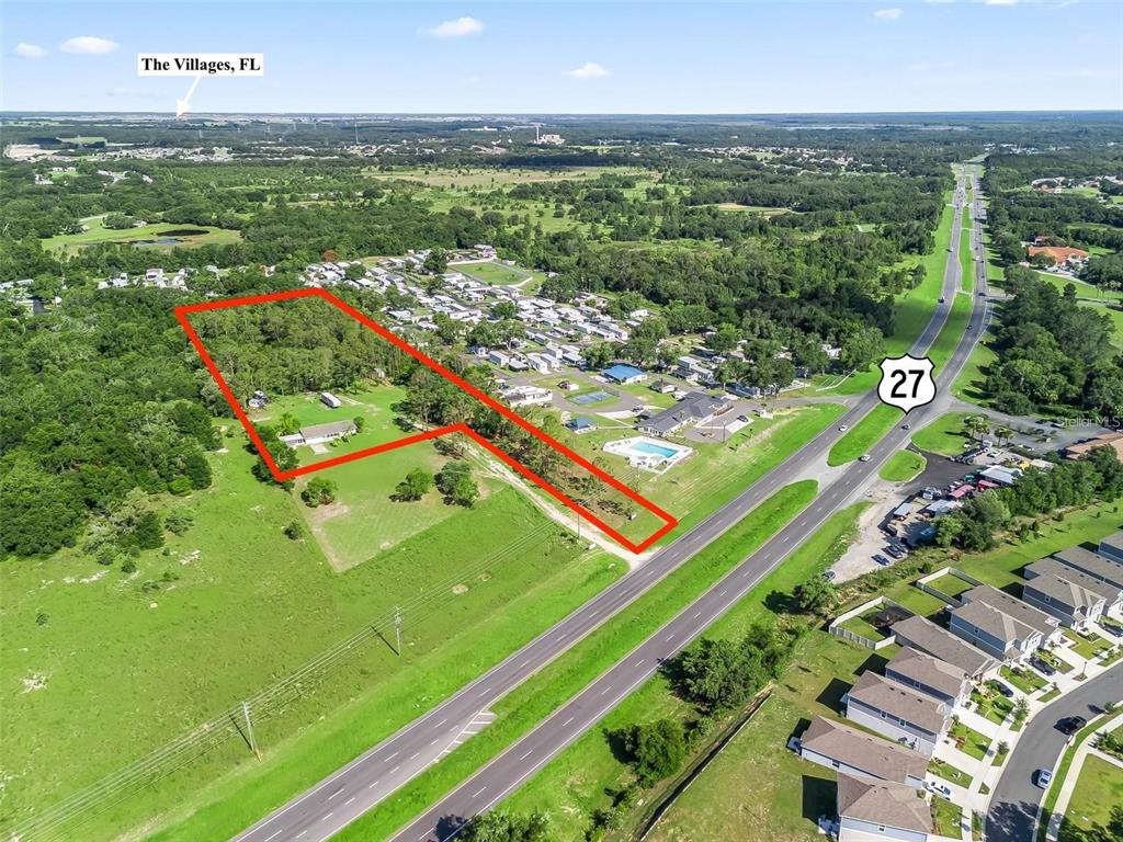 An aerial view shows a large, irregularly shaped property outlined in red next to a highway — 26043 US HIGHWAY 27, LEESBURG, FL