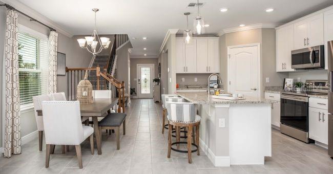 An open-concept kitchen and dining area features white cabinets, granite countertops, and tile flooring — 24254 NW 11TH LANE, NEWBERRY, FL