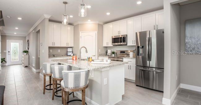 A modern kitchen features white cabinets, granite countertops, stainless steel appliances, and a breakfast bar — 24254 NW 11TH LANE, NEWBERRY, FL