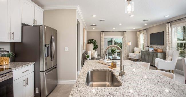 A kitchen island with a stainless steel sink overlooks an open-concept living area — 24254 NW 11TH LANE, NEWBERRY, FL