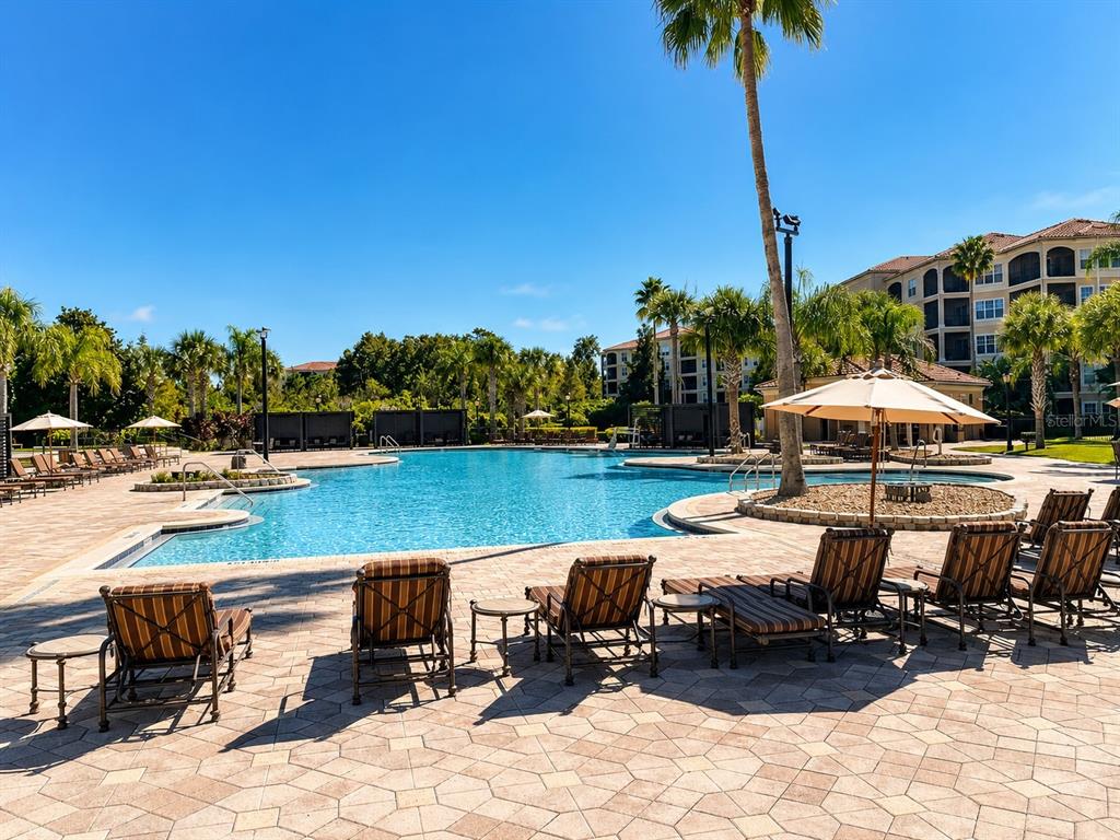 A large swimming pool surrounded by lounge chairs, palm trees, and multi-story apartment buildings — 8601 WORLDQUEST BOULEVARD UNIT 3201, ORLANDO, FL
