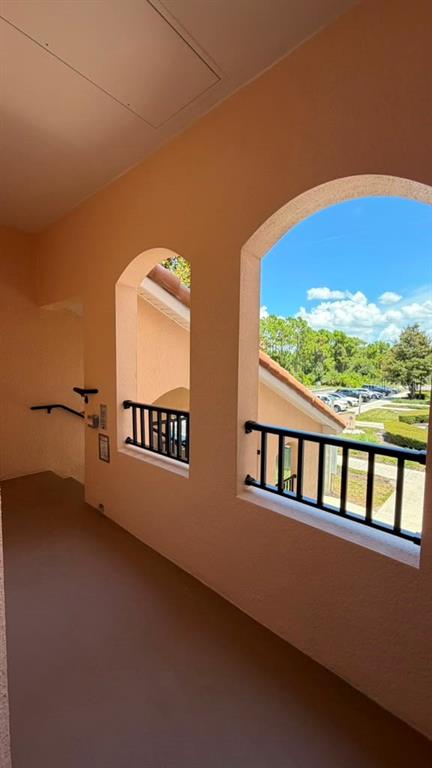 An open-air hallway with arched windows, black railings, and a view of a parking lot — 8601 WORLDQUEST BOULEVARD UNIT 3201, ORLANDO, FL