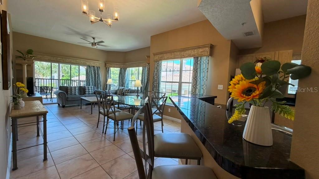 An open-concept living and dining area features tile floors, a kitchen island, and large windows — 8601 WORLDQUEST BOULEVARD UNIT 3201, ORLANDO, FL