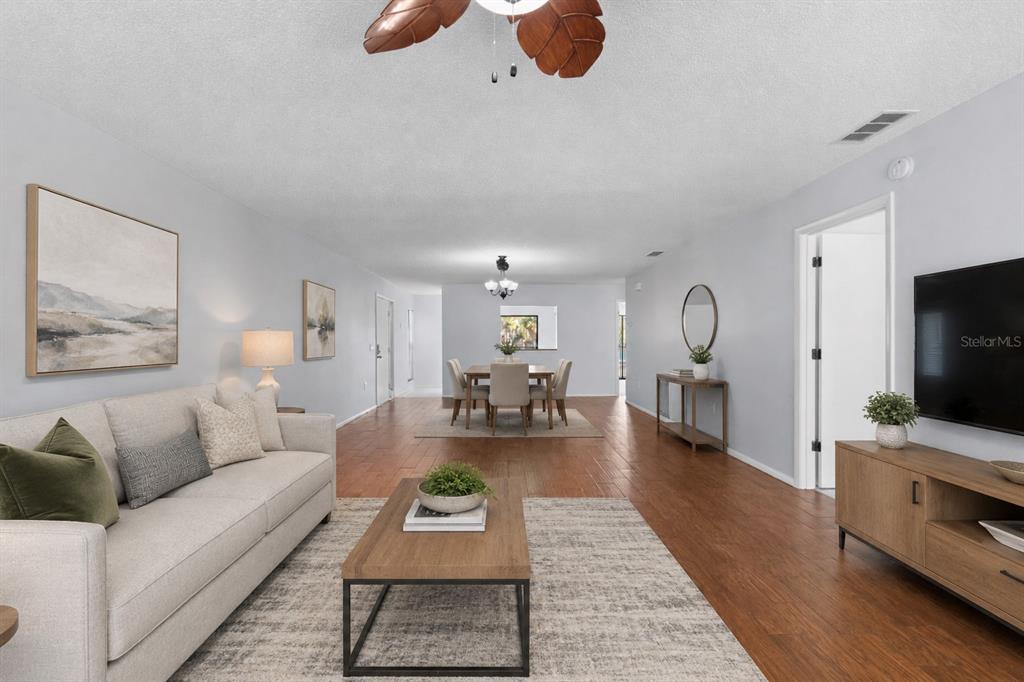 A living room and dining area with light gray walls, wood floors, and a ceiling fan — 6110 COUNTRY CLUB WAY UNIT 204, SARASOTA, FL