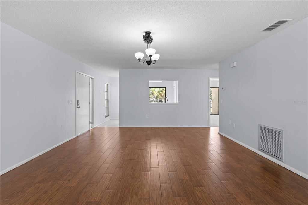 A living room with light gray walls, wood-look tile flooring, and a central light fixture — 6110 COUNTRY CLUB WAY UNIT 204, SARASOTA, FL