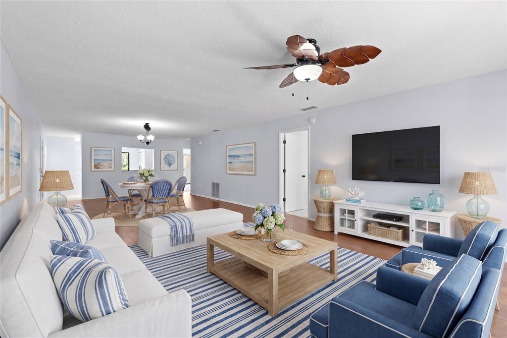 A living room with a white sofa, blue armchairs, a wooden coffee table, and dining area — 6110 COUNTRY CLUB WAY UNIT 204, SARASOTA, FL