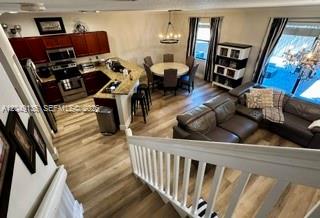 An open-concept kitchen and living area feature wood-look flooring and a white staircase railing — 16320 SW 71st Ter, Miami FL 33193, MIAMI, FL