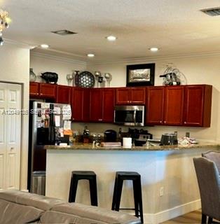 A kitchen features cherry wood cabinets, a stainless steel microwave, and a breakfast bar — 16320 SW 71st Ter, Miami FL 33193, MIAMI, FL