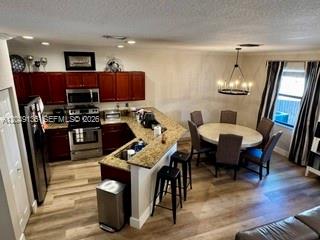 A kitchen with dark wood cabinets and granite countertops opens to a dining area — 16320 SW 71st Ter, Miami FL 33193, MIAMI, FL