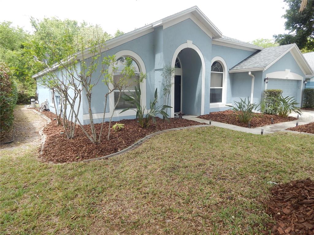 A light blue single-story house features an arched entryway and a front-facing garage — 5634 DONNELLY CIRCLE, ORLANDO, FL