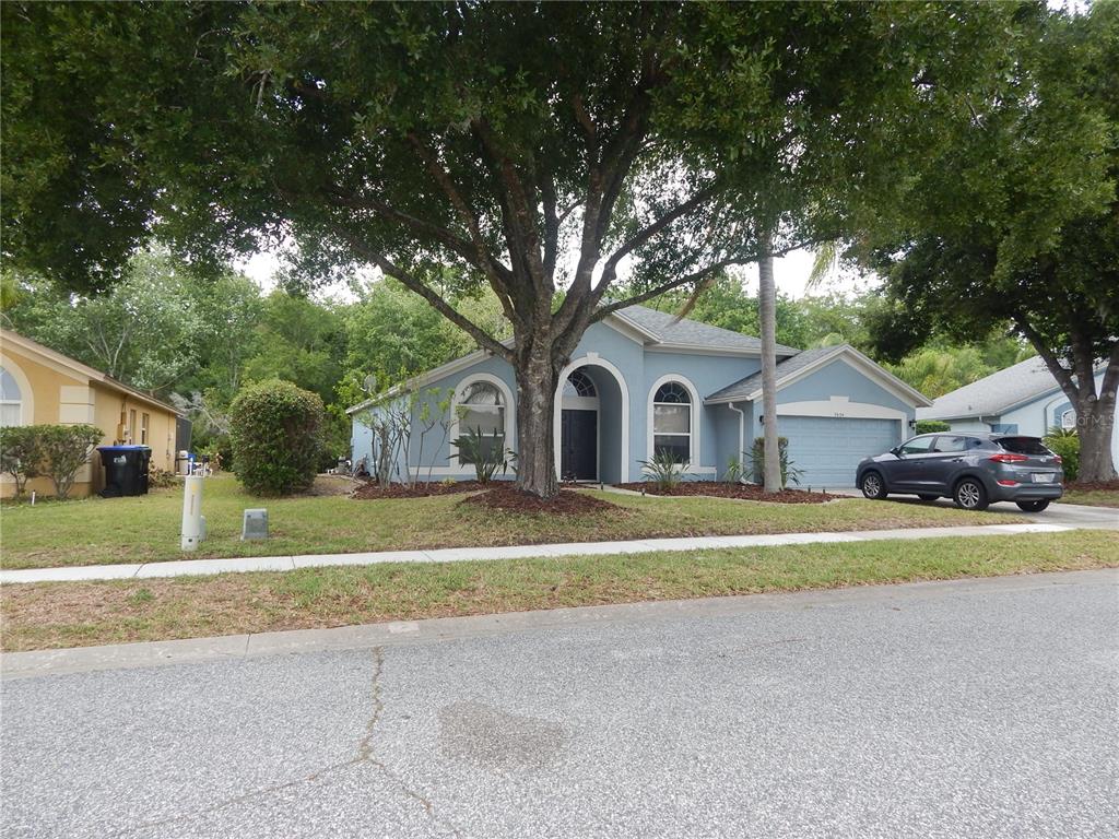 A single-story blue house with a large tree in the front yard — 5634 DONNELLY CIRCLE, ORLANDO, FL