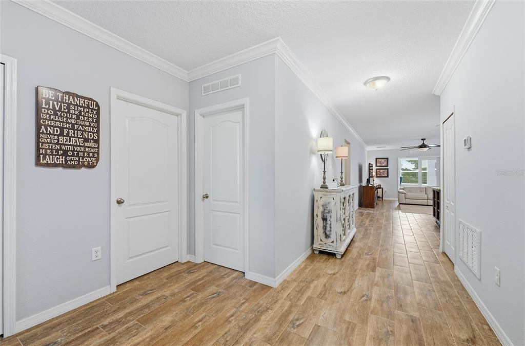 A hallway with wood-look tile flooring leads toward a living area with a ceiling fan — 186 FLATWOODS LOOP, DAVENPORT, FL