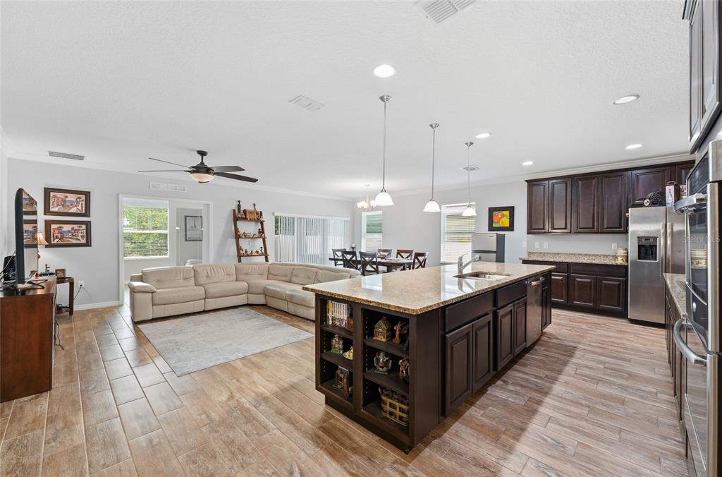 An open-concept kitchen and living area features dark wood cabinets, granite countertops, and tile flooring — 186 FLATWOODS LOOP, DAVENPORT, FL