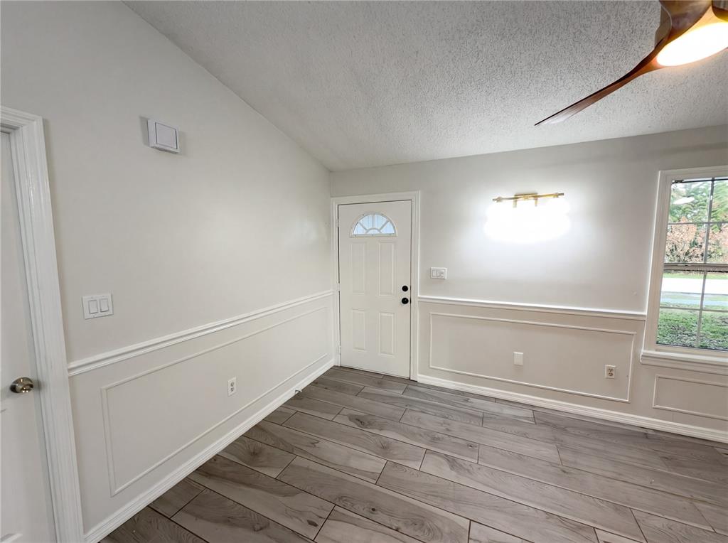 An interior room features light-colored walls with wainscoting, wood-look tile flooring, and a front door — 967 LAMPLIGHTER DRIVE NW, PALM BAY, FL