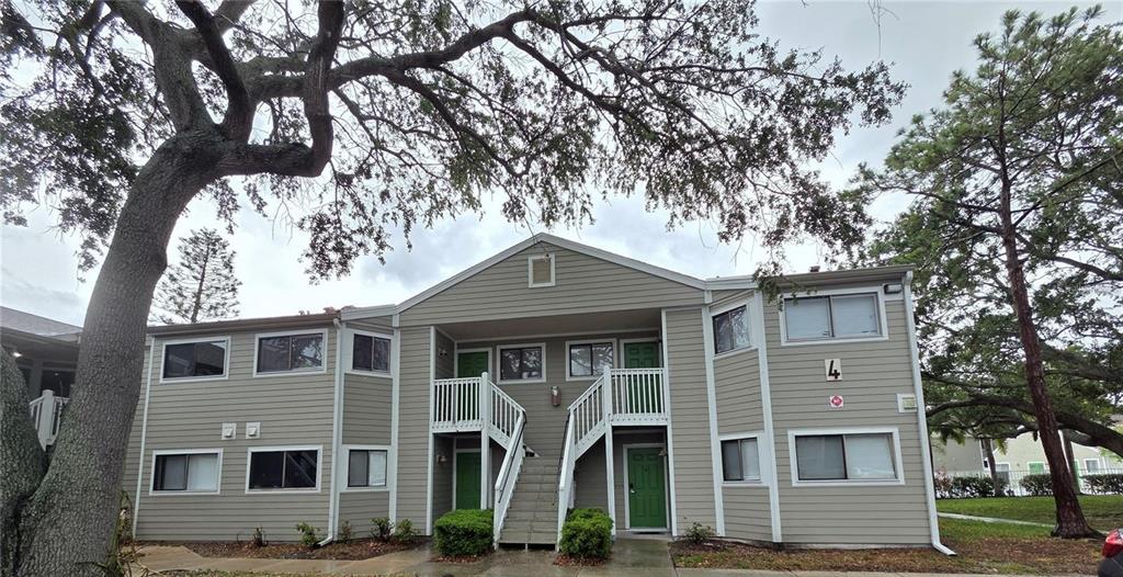 A two-story apartment building with beige siding, green doors, and an exterior staircase — 7298 ULMERTON ROAD UNIT 602, LARGO, FL