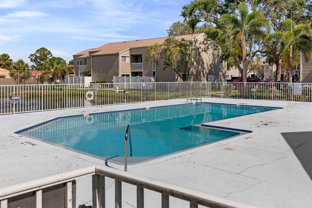 A rectangular swimming pool sits on a concrete deck surrounded by a white metal fence — 7298 ULMERTON ROAD UNIT 602, LARGO, FL
