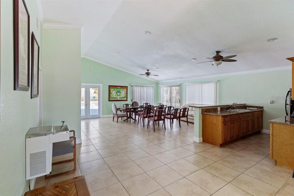 A spacious open-concept room features tile flooring, a kitchen island, and a dining area — 7298 ULMERTON ROAD UNIT 602, LARGO, FL