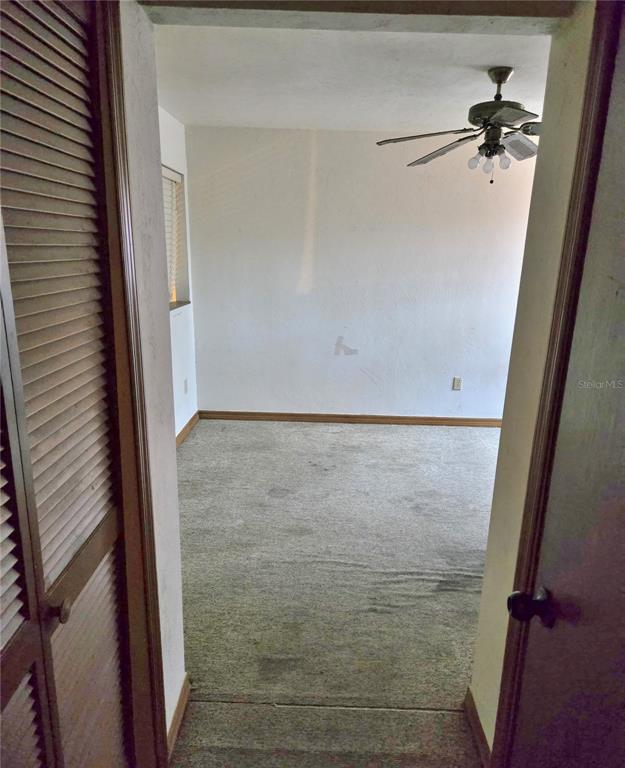 A view through a doorway into a carpeted bedroom with a ceiling fan — 5727 SW 10TH PLACE, GAINESVILLE, FL