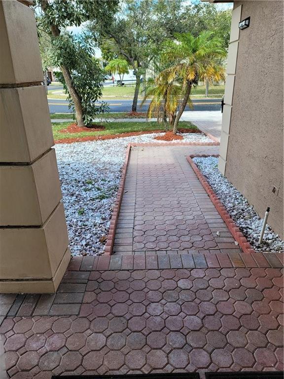 A paved walkway leads from a covered porch toward a street with trees and landscaping — 2281 SW 164th Avenue, Miramar FL 33027, MIRAMAR, FL