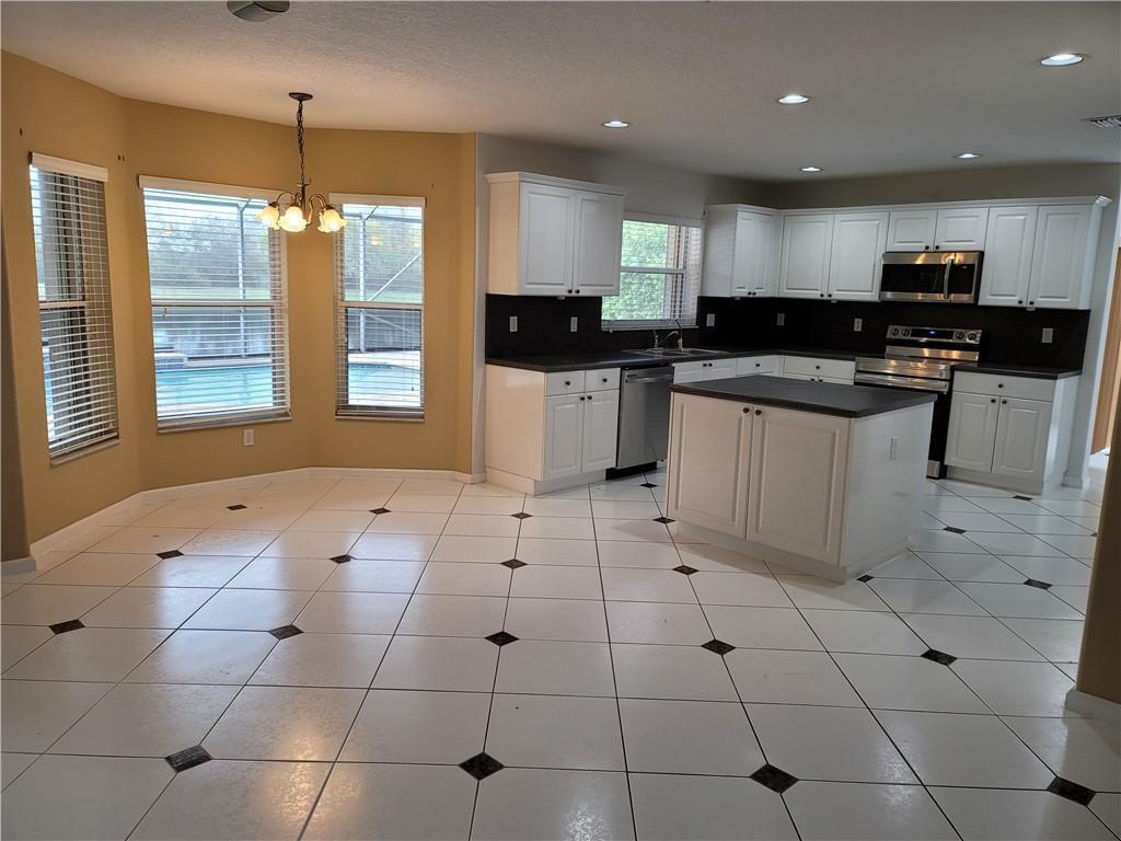 A kitchen with white cabinets, dark countertops, and white tile flooring with black accents — 2281 SW 164th Avenue, Miramar FL 33027, MIRAMAR, FL