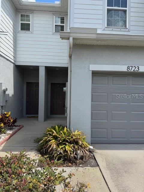 The exterior of a two-story townhouse features a gray garage, two entry doors, and landscaping — 8723 TURNSTONE HAVEN PLACE, TAMPA, FL