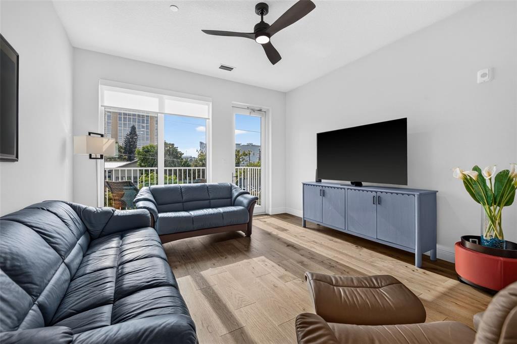 A living room features blue leather sofas, a television on a blue console, and hardwood floors — 600 3RD AVENUE S UNIT 207, ST PETERSBURG, FL