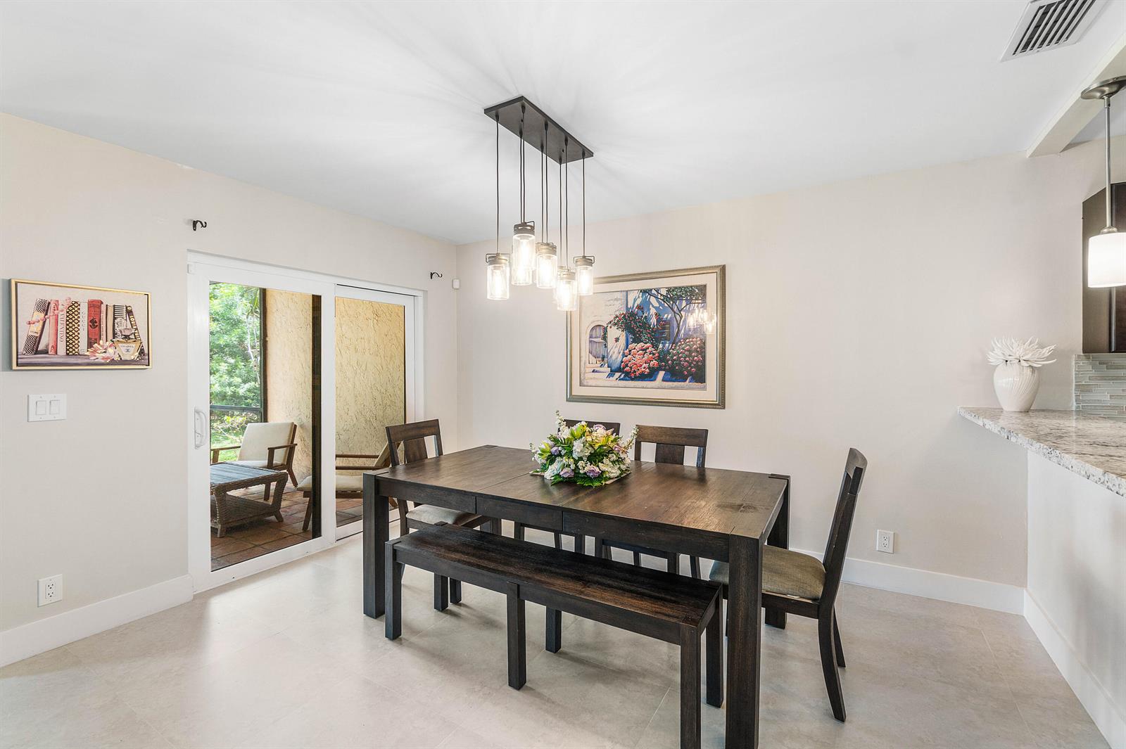 A dining room features a dark wood table, a bench, chairs, and a glass pendant light — 6044 Glendale Drive, Boca Raton FL 33433, BOCA RATON, FL