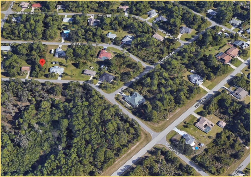An aerial view shows a residential neighborhood with houses, wooded lots, and intersecting streets — 5410 STOKES STREET, PORT CHARLOTTE, FL