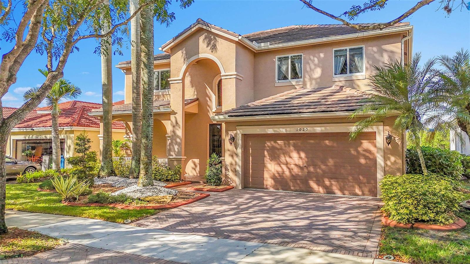 A two-story tan stucco house with a tiled roof and a two-car garage — 1020 Lavender Circle, Weston FL 33327, WESTON, FL