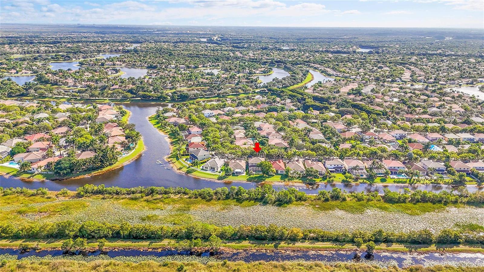 An aerial view of a residential neighborhood featuring houses along a canal and wetlands — 1020 Lavender Circle, Weston FL 33327, WESTON, FL