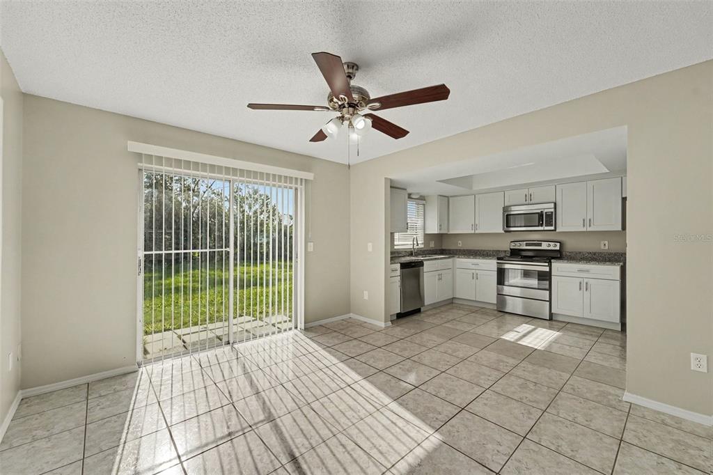A kitchen with white cabinets and stainless steel appliances opens to a tiled dining area — 1822 JASPER DRIVE, ORLANDO, FL