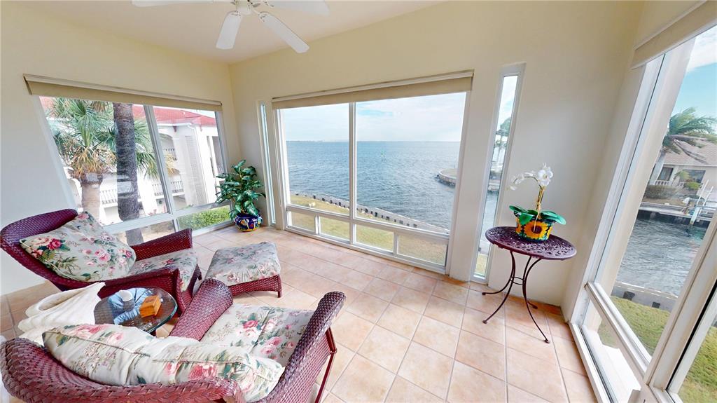 A sunroom with wicker furniture, tile flooring, and large windows overlooking a body of water — 1 COLONY POINT DRIVE UNIT 5C, PUNTA GORDA, FL