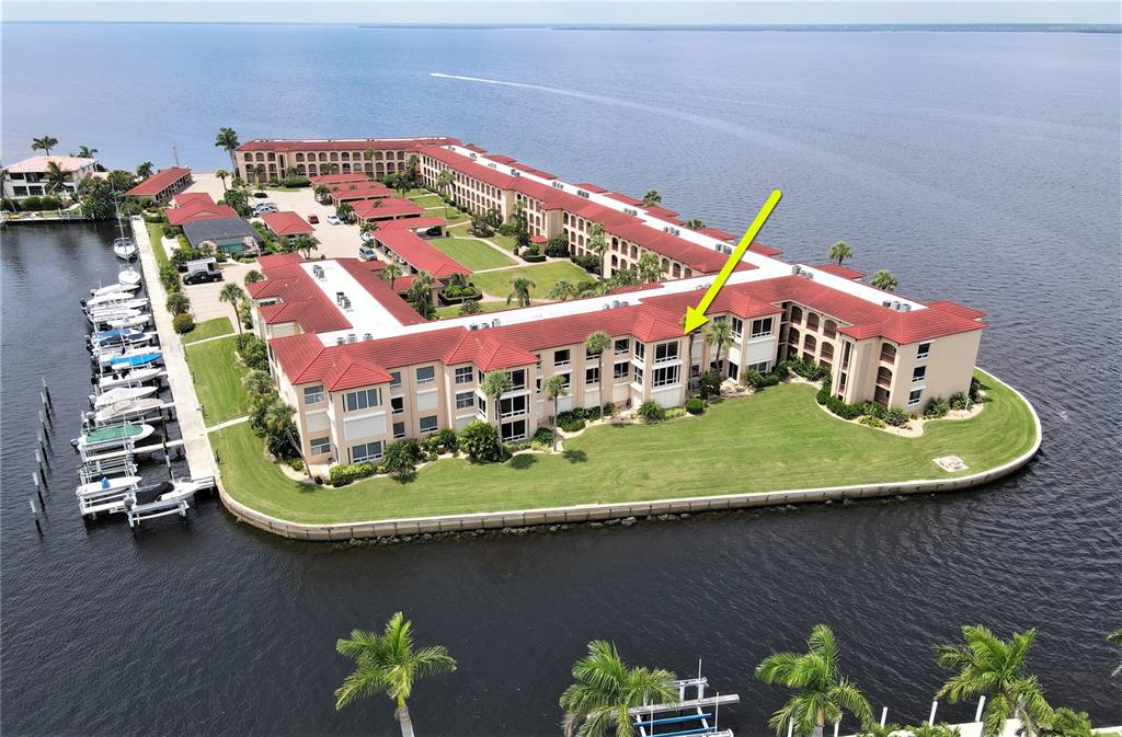 An aerial view of a waterfront condominium complex with a yellow arrow pointing to a unit — 1 COLONY POINT DRIVE UNIT 5C, PUNTA GORDA, FL
