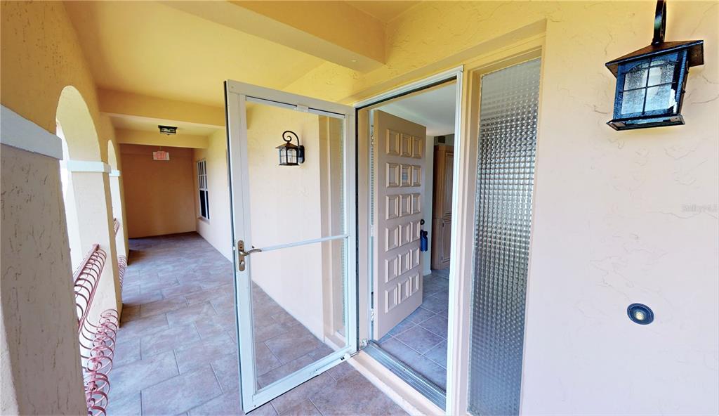 An open screen door leads to an entryway with a tiled floor and textured walls — 1 COLONY POINT DRIVE UNIT 5C, PUNTA GORDA, FL