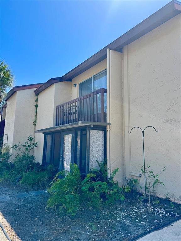 A two-story building exterior features a ground-level enclosed patio and an upper-level wooden balcony — 2632 HIDDEN LAKE DRIVE N UNIT E, SARASOTA, FL