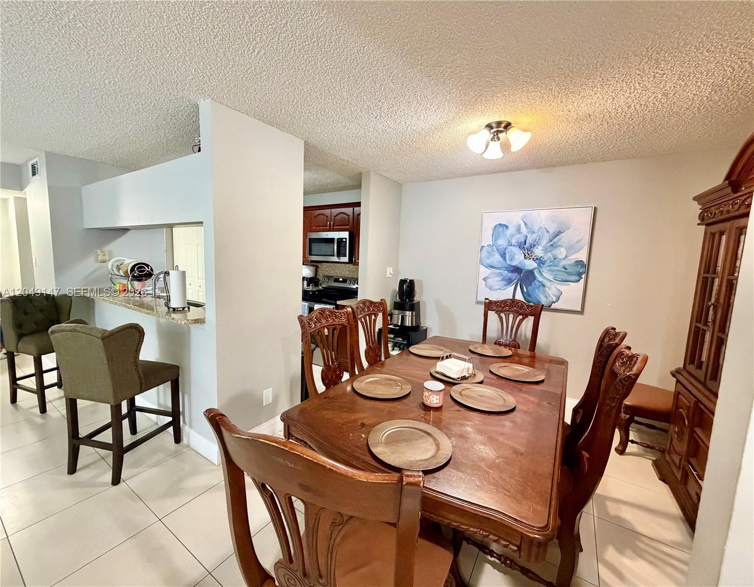 A dining area with a wooden table and chairs sits adjacent to a kitchen pass-through — 10521 SW 158th Ct # 203, Miami FL 33196, MIAMI, FL