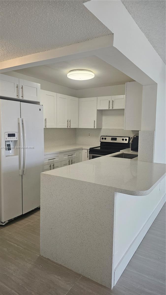 A kitchen features white cabinets, light countertops, a white refrigerator, and a breakfast bar — 5625 W 20th Ave # 208, Hialeah FL 33012, HIALEAH, FL