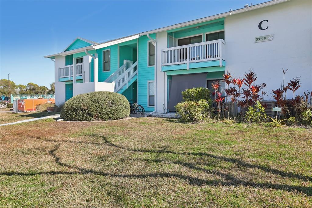 A two-story apartment building with teal accents, white railings, and a landscaped lawn — 455 ALT 19 S UNIT 42 & 46, PALM HARBOR, FL