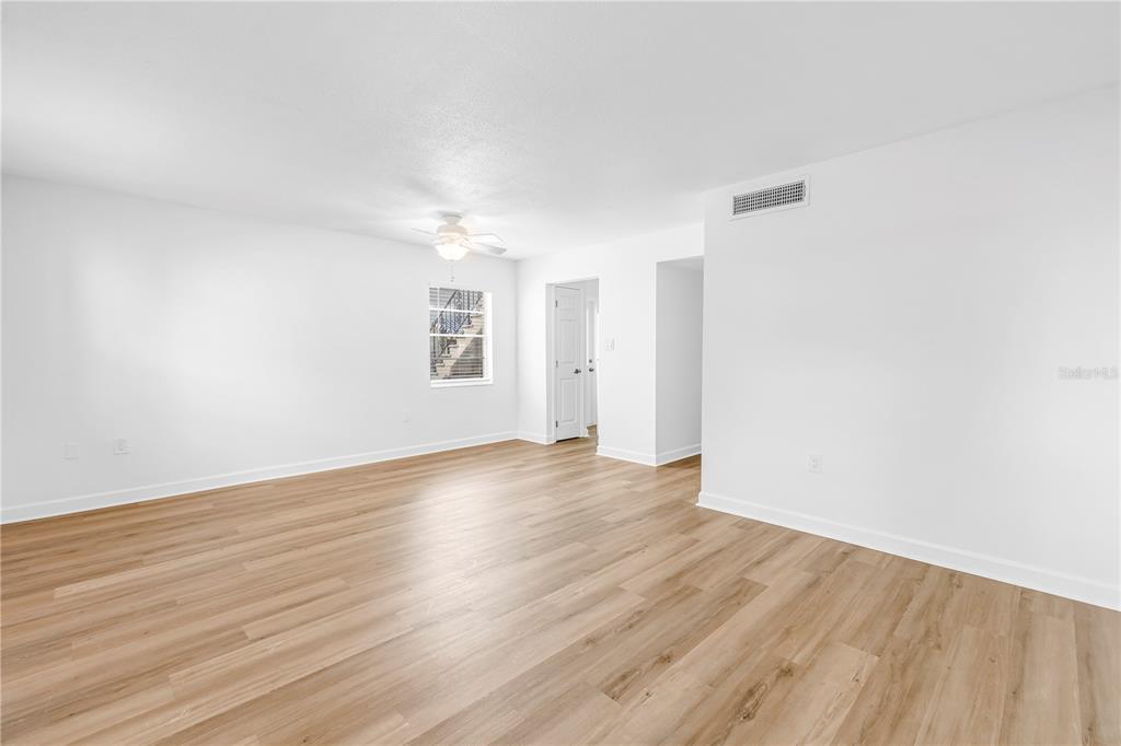 An empty room with white walls, light wood-look flooring, a ceiling fan, and a window — 6960A SUNSET DRIVE S UNIT 1B, SOUTH PASADENA, FL