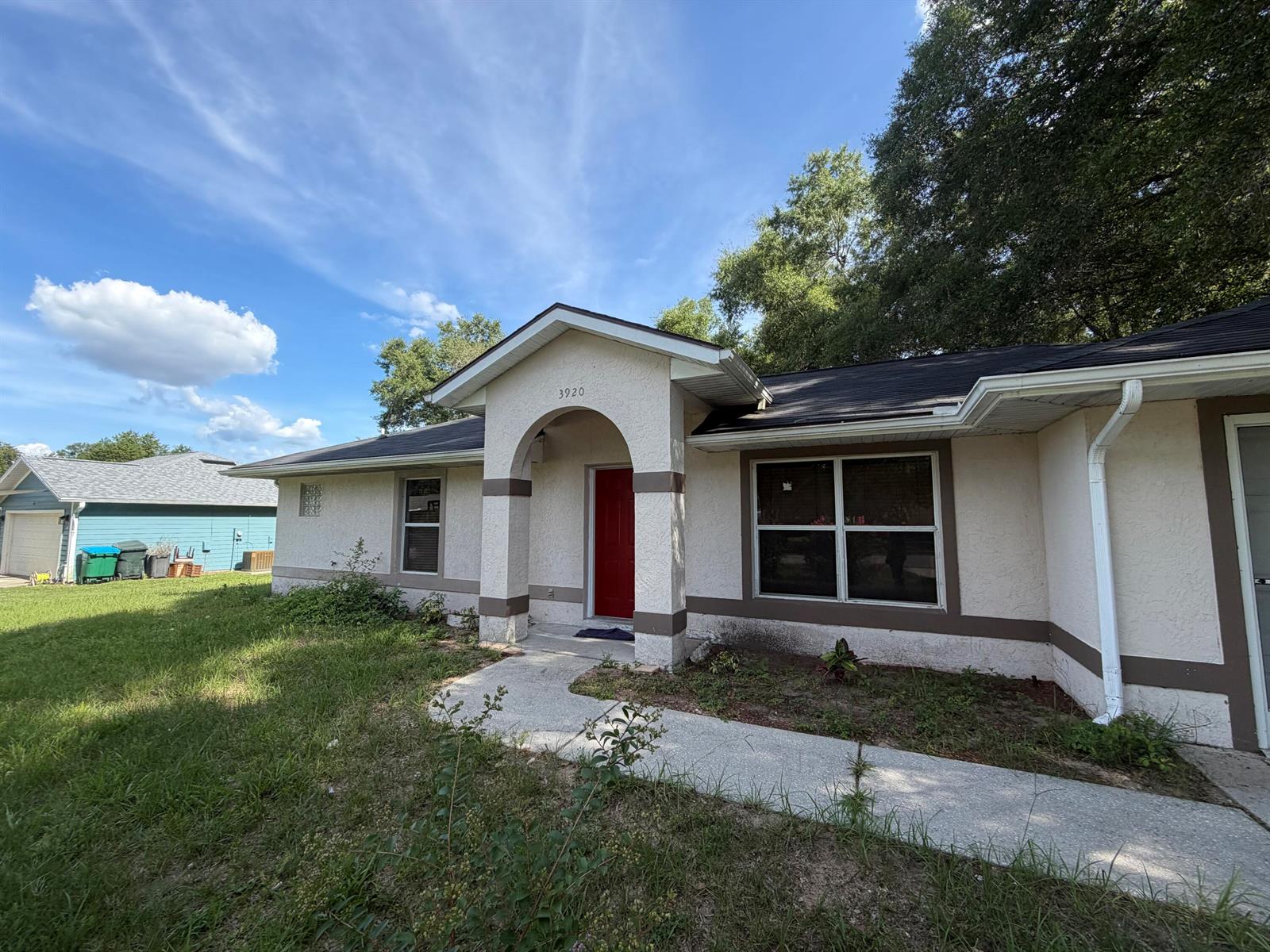 A single-story house with a stucco exterior, a red front door, and a concrete walkway — 3920 E Allendale Street, Inverness FL 34453, INVERNESS, FL
