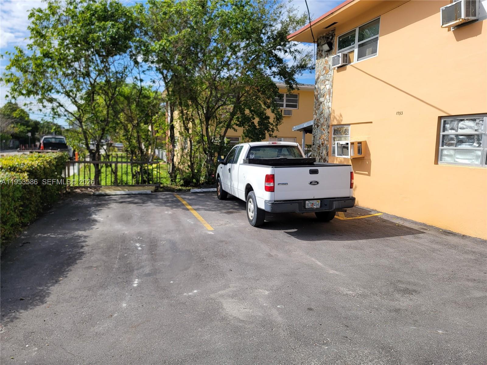 A white pickup truck is parked in a paved lot next to a yellow building — 1753 SW 6th St, Miami FL 33135, MIAMI, FL