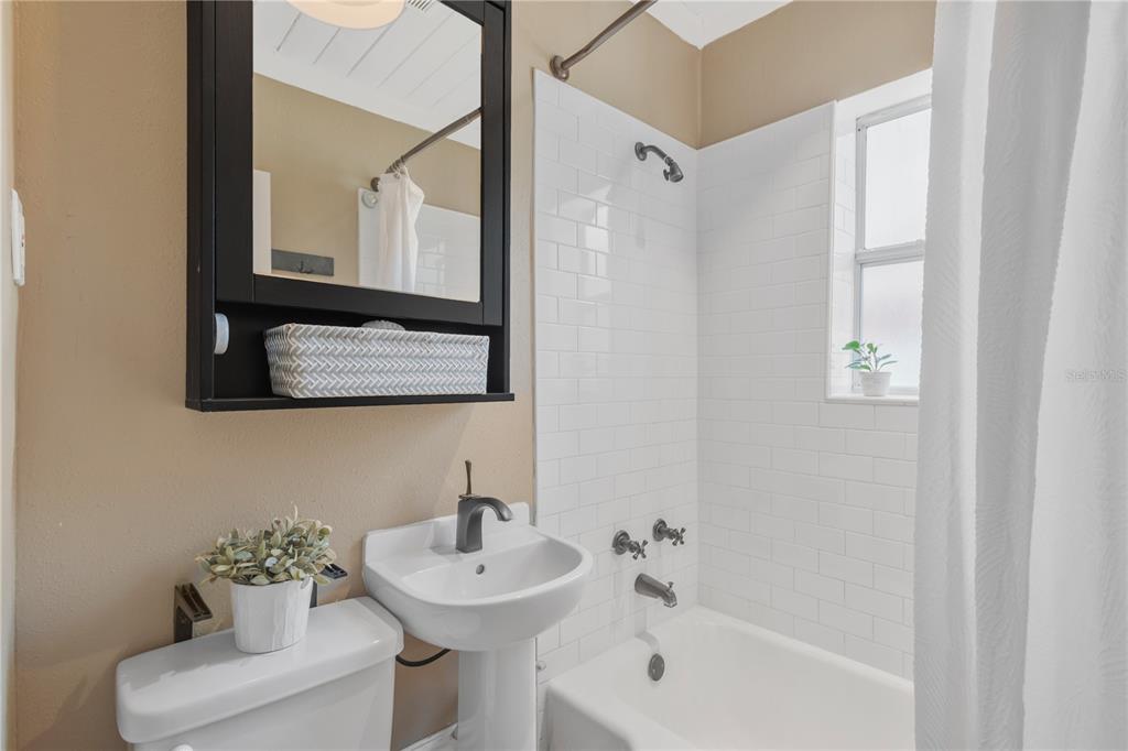 A bathroom features a pedestal sink, a toilet, and a white subway-tiled shower-tub combination — 1315 E OSBORNE AVENUE, TAMPA, FL