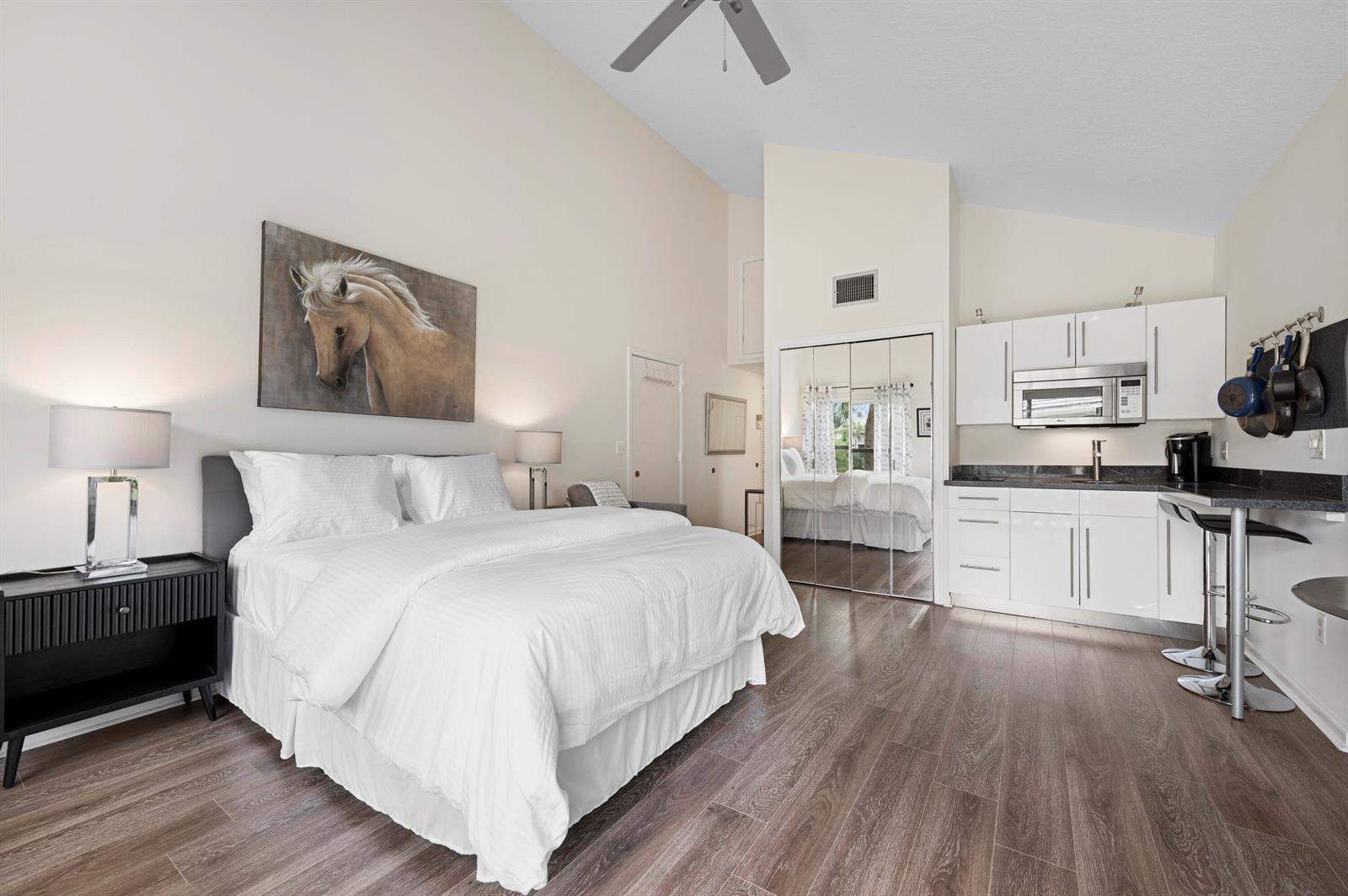 A bedroom with a vaulted ceiling, a bed, an armchair, and a small dining table — 11863 Wimbledon Circle # 543, Wellington FL 33414, WELLINGTON, FL
