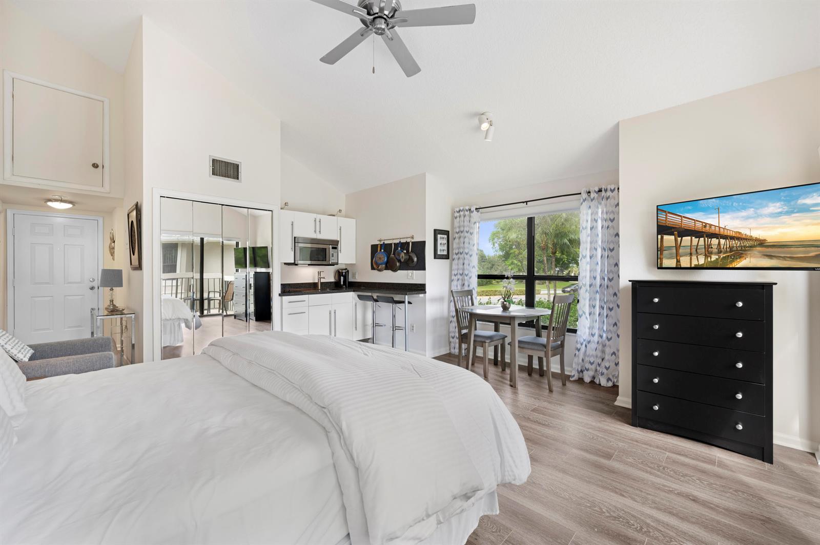 A bedroom with a bed, a dresser with a television, and a desk near a window — 11863 Wimbledon Circle # 543, Wellington FL 33414, WELLINGTON, FL